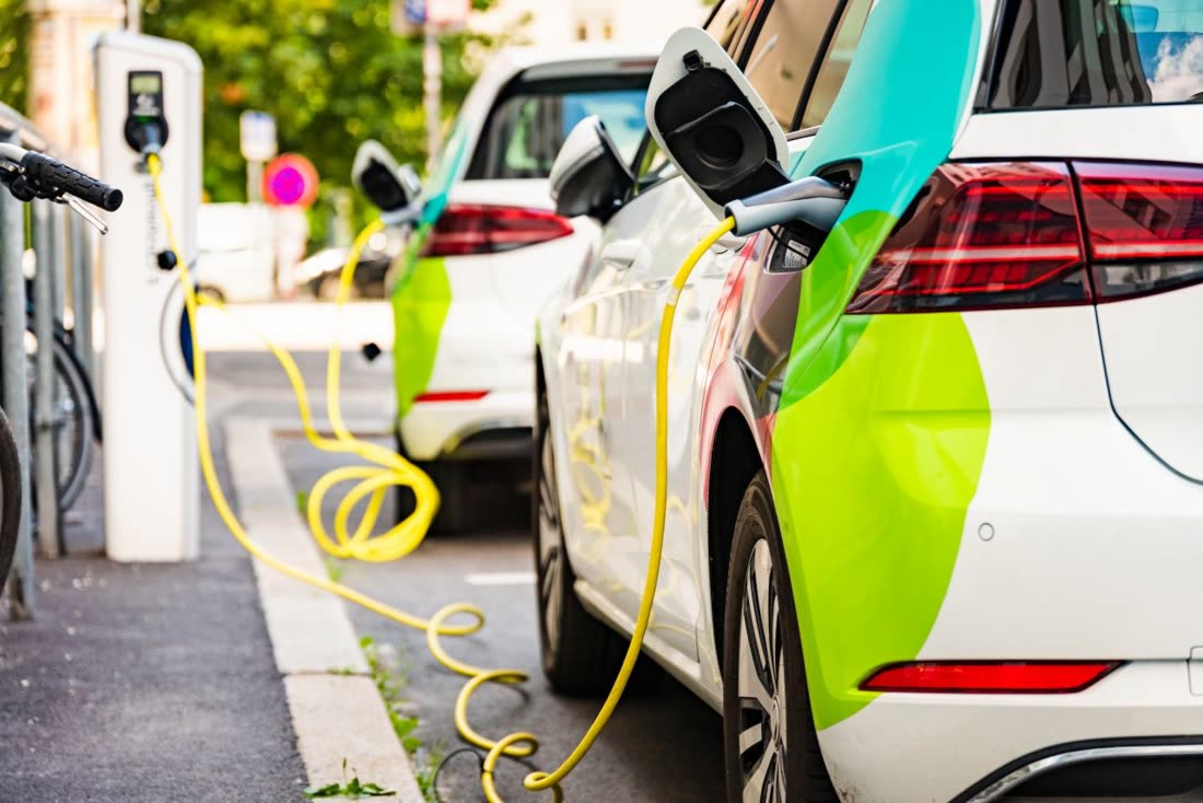 Coche eléctrico cargando batería en estación urbana