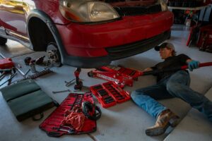 Técnico reparando los bajos de un vehículo en taller mecánico